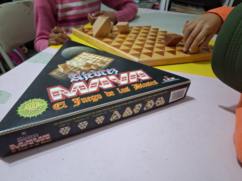 Juego de mesa con piezas geométricas mientras niñas y niños participan.