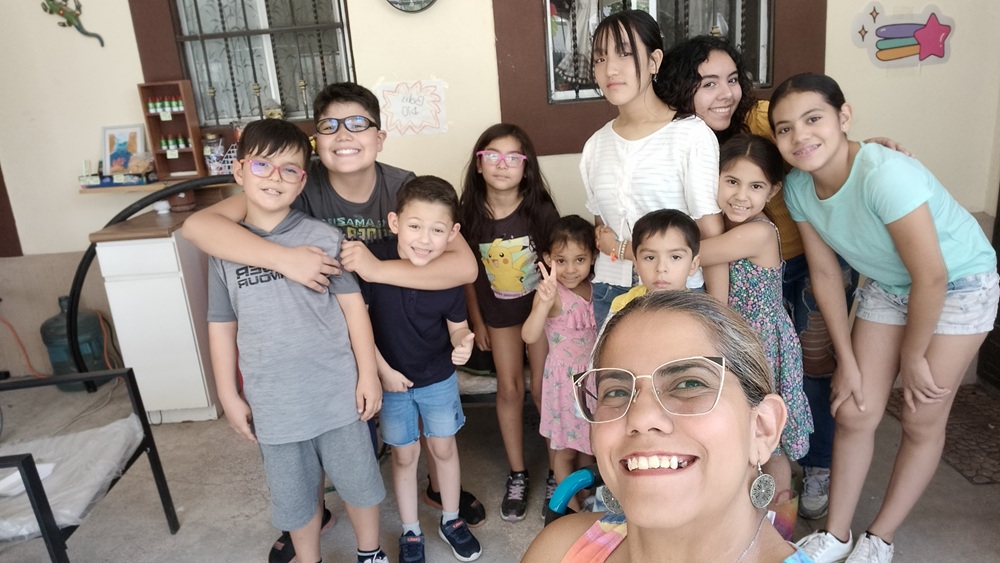 Mujer tomándose una selfie con niñas y niños en un espacio comunitario.