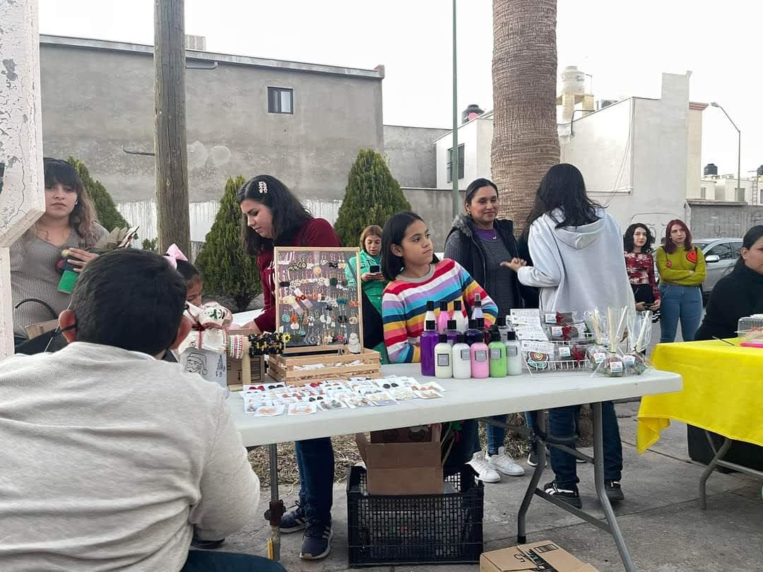 Personas en un encuentro comunitario con exhibición de productos artesanales.
