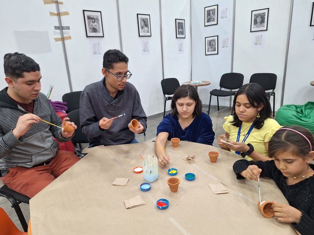 Personas pintando macetas en un taller.
