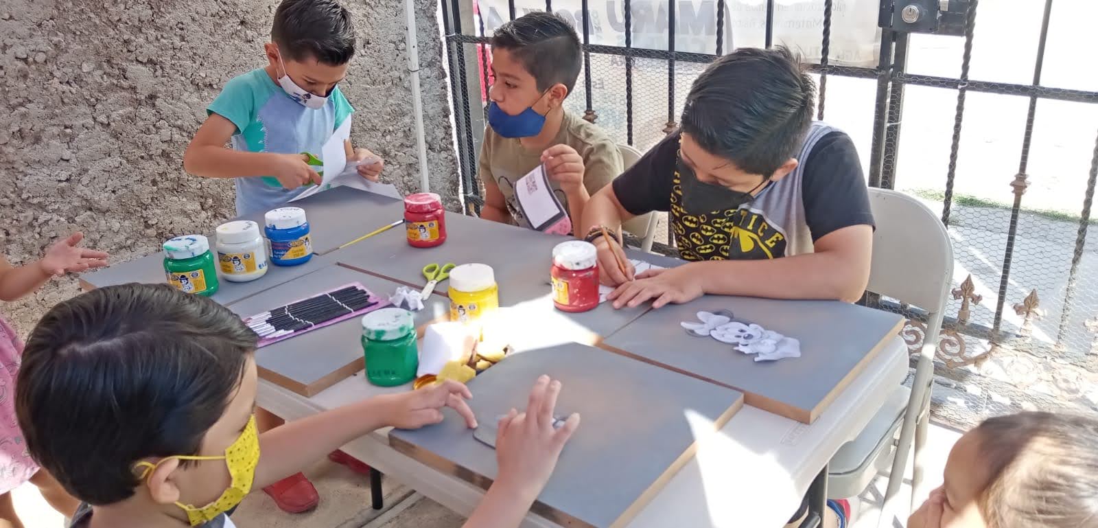 Niñas y niños recortando y pintando materiales en una actividad.