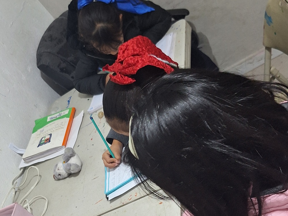 Niñas escribiendo en sus cuadernos durante una actividad escolar.