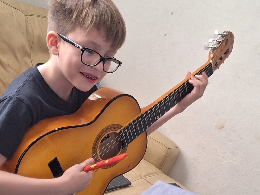 Niño tocando una guitarra en un taller.